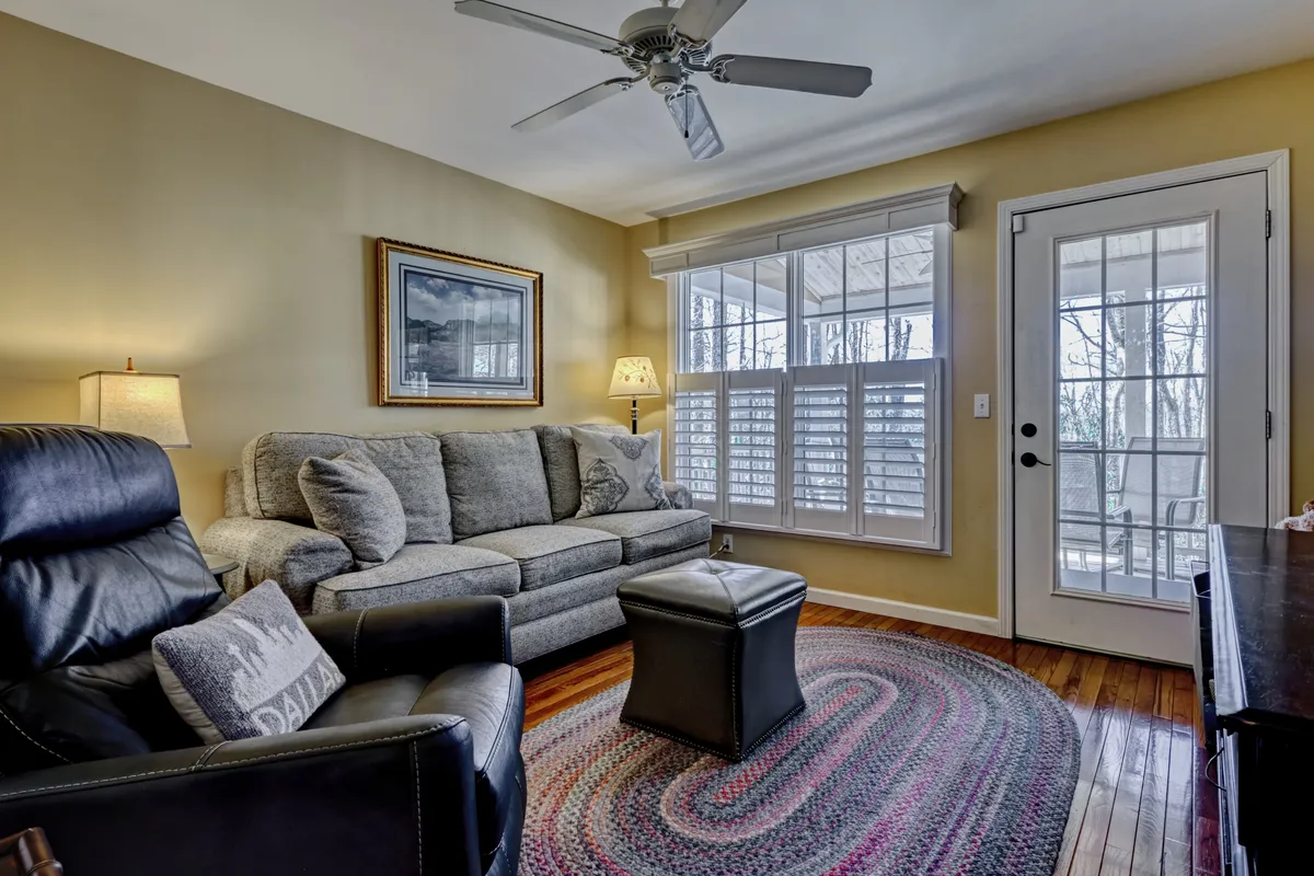 A cozy living room scene with a comfortable sofa, coffee table, and large window that lets in plenty of sunlight. The inviting arrangement is complemented by a lamp, artwork, and a warm ambiance, suggesting a space perfect for socializing or unwinding after a day of group adventures.